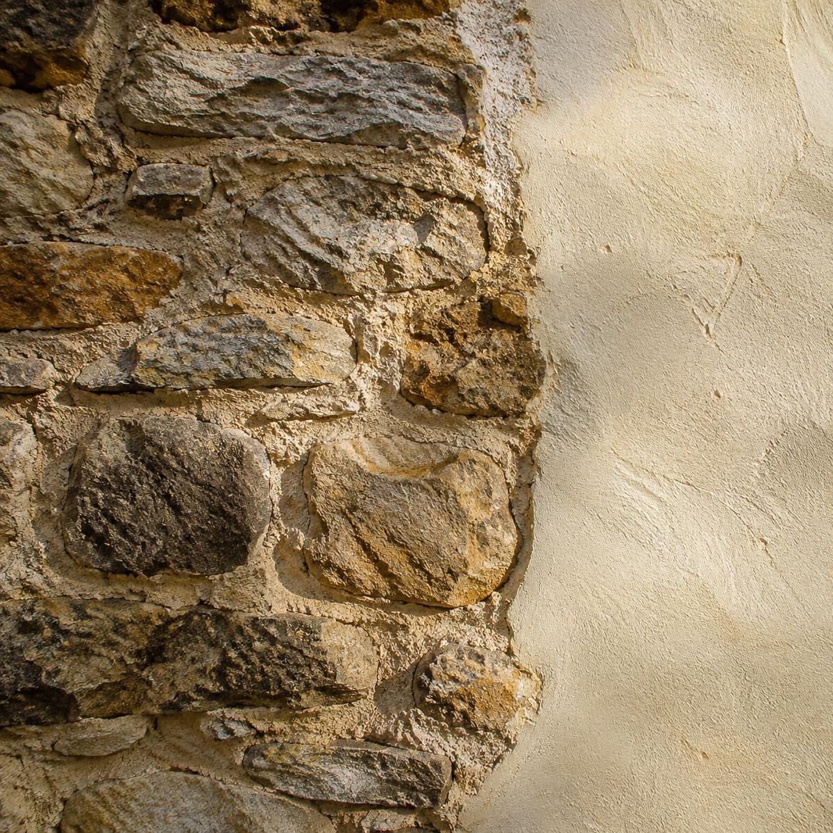 Muro de piedra antiguo junto a revoco de cal nuevo