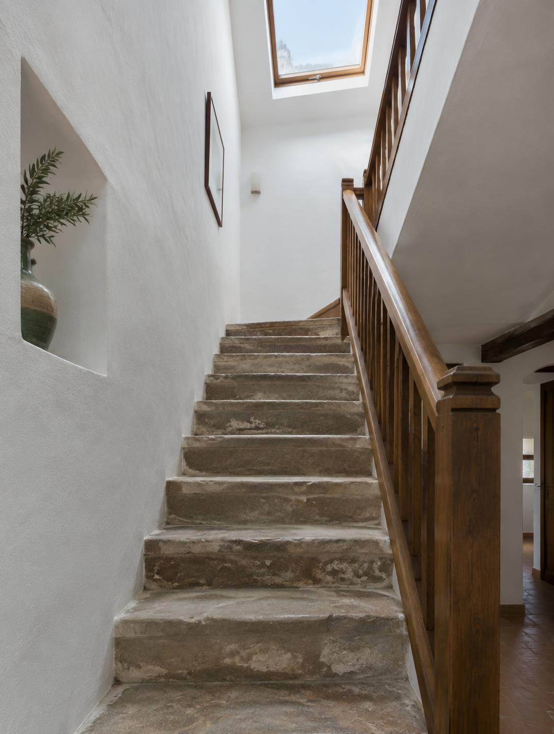 Escalera de piedra con barandilla de madera restaurada